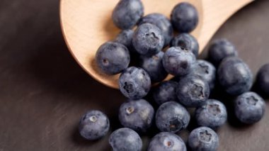 Tahta bir kaşıkta toplanmış taze yabanmersini meyveleri. Böğürtlen hasadı. Döndürme. Kırsal görünüm