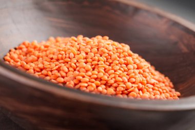 Çiğ organik kırmızı mercimek tanecikli Rustik ahşap kase. Yüksek protein mısır gevreği ürünü. Pişmemiş portakal taneleri.