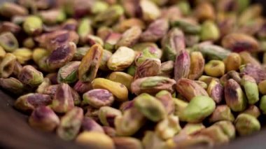 Kabuksuz kabuklu fıstıklar besleyici fındık çekirdekleri ile dolu bir ahşap kaseye düşerler. Diyet sağlıklı yemek. Döndürme