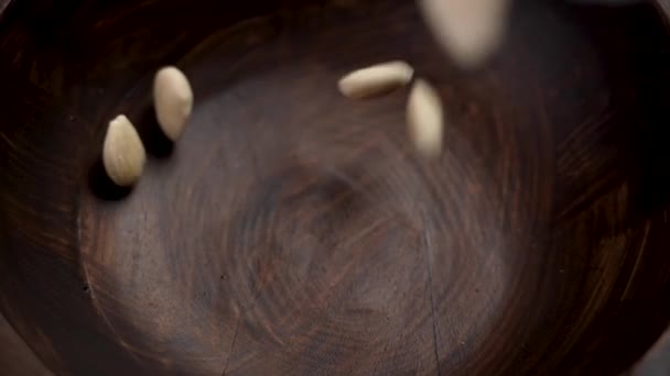 扁平的花瓣杏仁掉进了一个木制盘子里 壳生坚果 即食健康食品近餐 慢动作 — 图库视频影像