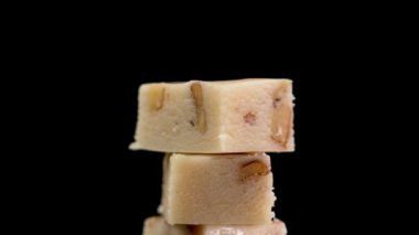 Siyah arka planda badem ve nougat bulunan İspanyol Noel Turronu. El, tatlı dilimleri yakın çekim alıyor.