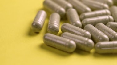Renkli sarı arka planda reçeteli bitkisel vitamin kapsülleri yakın plan. Döndürme