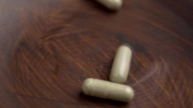 Bitkisel takviye vitamin kapsülleri ahşap bir kaseye düşüyor. Reçeteli doğal haplar. Bitki ilacı hapları.