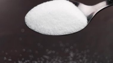 Stevia şekeri, tatlı kaşığındaki tozu yakın çekim ile değiştiriyor. Ağır çekimde serpiştiriyor