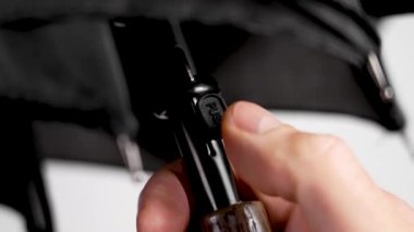 Siyah otomatik şemsiyeyi beyaz arkaplanda, sapında düğme olan bir şekilde açıyorum