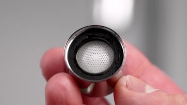 Su musluğu havalandırma filtresi ve su tesisatçısının elindeki lastik conta.