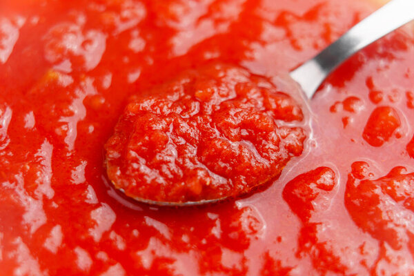 Red fresh tomato sauce in spoon. Traditional italian recipe. Close up. 