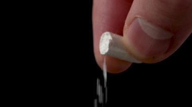 Beyaz tıbbi toz, elinde siyah bir arka plan bulunan açık bir ilaç kapsülünden akıyor. Uyuşturucu ve bilimsel araştırma kavramı