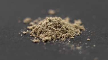 Siyah bir arka planda ilave haptan elde edilen kurutulmuş şifalı bitki tozu. Alternatif bitkisel tıp konsepti. Döndürme. Makro çekim