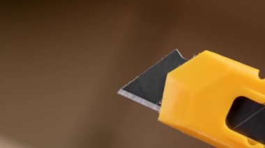 Açık bir paket kutusundaki sarı alet bıçağı. Geri çekilebilir karton kesiciyi kapat.