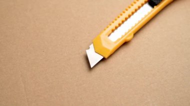 Kahverengi bir Kraft karton arka planda paketleri açmak için kullanılabilir bıçak ya da çekilebilir maket bıçağı. Döndürme