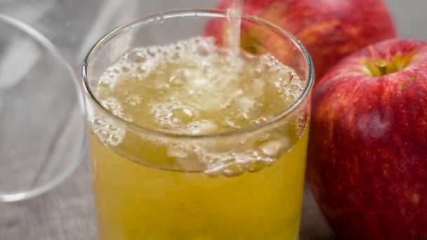 赤い有機リンゴと空の落ちたガラスが付いているテーブルの輝く泡が付いているAppleのサイダー泡は近づきます スペインの伝統的なバー アルコール飲料 — ストック動画