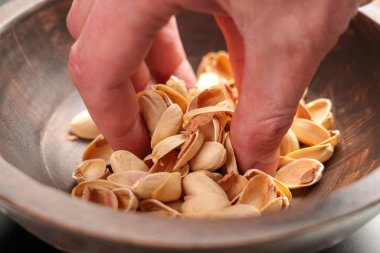 Ev atığı ayıklama. Tahta bir kaseden fıstık kabuğu fırlatıyorlar. Yaklaş.