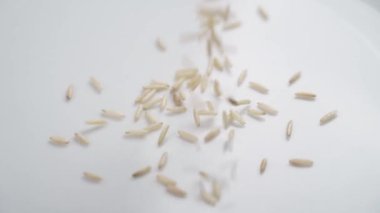 Cilalanmamış yabani basmati pirinci paketten seramik beyaz bir tabağa düşüyor. Yavaşça yaklaşın.