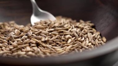 Süt devedikeni demleme işlemi. Metal bir kaşık, ahşap bir kaseden kurumuş tohumları topluyor.