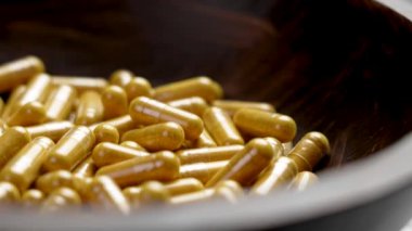 Tahta tabakta Curcuma bitkisel ilaç hapları. Zerdeçal tozlu sarı tıbbi kapsüller. Döndürme