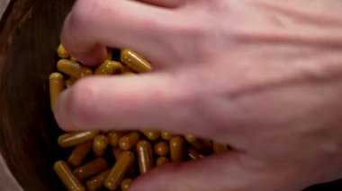 Hasta eli, bir avuç zerdeçal takviye kapsülü alıyor ve kükürt özünü kapatıyor.