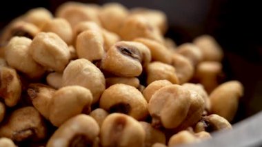 Organik tuzlu kavrulmuş kurutulmuş mısır taneleri ahşap kasede yakın plan. Döndürme. Kızarmış mısırın lezzetli birası.