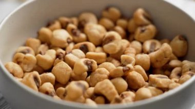 Mutfak kasesi ve tuzlanmış közlenmiş kuru mısır taneleri ağır çekimde. Kızarmış mısırın lezzetli birası. Döndürme