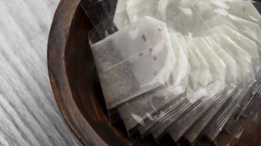 Ahşap kasede şeffaf politen paketlerle kurumuş bitkisel yapraklarla yeni çay poşetleri. Döndürme