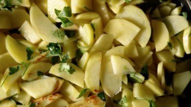 Kızartma tavasında taze bitkisel kişniş soslu dilimlenmiş patates. Organik lezzetli garnitür.