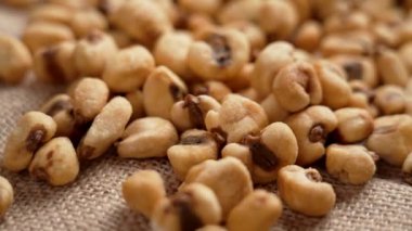 Kavrulmuş tuzlu mısır taneleri, ağır çekimde kırsal bir kumaşın üzerine düşüyor. Kızarmış mısır çerezi. Döndürme