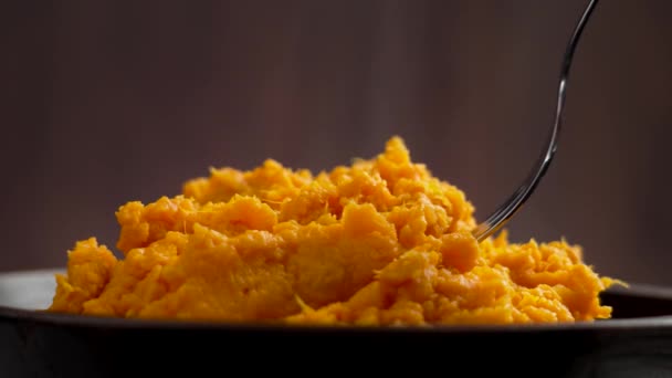 新鮮に作られたホットマッシュスイートジャガイモをフォークで食べ 木製の壁の背景にスチームを閉じます 自家製調理されたヤムピューレ — ストック動画