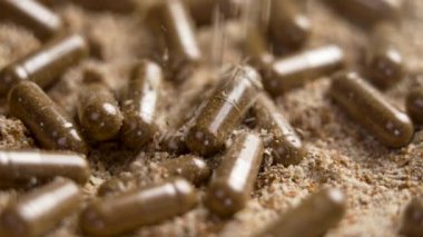 Süt devedikeni takviyesi kapsülleri ve düşen bitkisel özü içeren Silybum Marianum bitkisi tozu. Alternatif ilaç hapları. Silymarin kaynağı. Ağır çekim. Döndürme