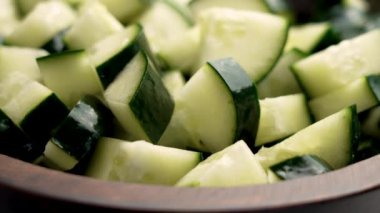 Kırsal ahşap kasede taze doğranmış yeşil salatalık yakın plan. Sağlıklı sebze salatası malzemeleri. Döndürme