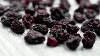 Dokulu mutfak tahtasındaki tatlı kuru kiraz. Yaklaş. Besleyici kurutulmuş meyveler. Sağlıklı vitamin bileşeni. Üst Manzara. Döndürme