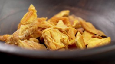 Ahşap kasede kurumuş mango parçaları. Dilimlenmiş kurutulmuş meyveler yakın mesafede. Sağlıklı atıştırmalıklar. Döndürme