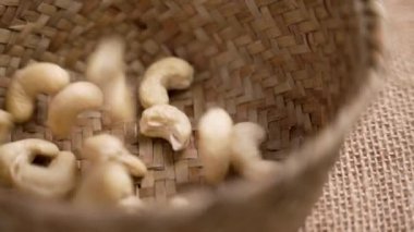 Erdemli kaju fıstığı ağır çekimde hasırlı bir tencereye düşüyor. Keto diyet malzemeleri. Döndürme