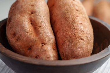 Mutfak ahşap kasesinde pişmemiş tatlı patates (tatlı patates). Çiğ batata kökleri. Sebze diyeti malzemesi.. 