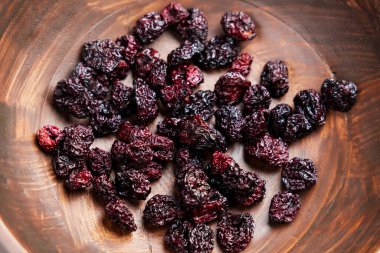 Kırsal ahşap çanakta tatlı kuru kiraz. Yaklaş. Besleyici kurutulmuş meyveler. Sağlıklı vitamin bileşeni. Üst Manzara. Döndürme