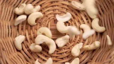 Çiğ kaju fıstığı ağır çekimde rattan hasır bir ekolojik kaseye düşüyor. Organik sağlıklı malzeme. Döndürme