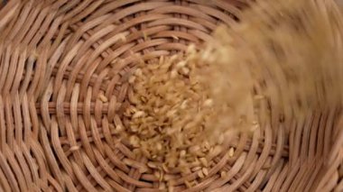 Organik altın keten tohumları yavaş çekimde ekolojik rattan kabına dökülüyor. Omega 3 gıda takviyesi. Döndürme. Üst görünüm