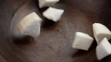 Kasava kökü yavaş çekimde kırsal bir ahşap kaseye düşüyor. Çiğ Manioc rhizome. Sağlıklı sebze yemeği.