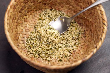 Çiğ kenevir taneleri (kenevir sativa tohumları) kırsal hasır sepetinde metal kaşıkla. Sağlıklı gıda takviyesi.