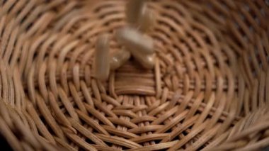 Kahverengi toz bitkisel ilaç kapsülleri ve bitki özleri üreme sistemi için yavaş çekimde organik bir rattan kasesine düşüyor.