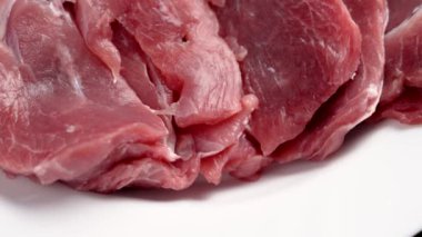 Taze dilimlenmiş hindi eti. Beyaz bir tabakta çiğ tavuk fileto. Döndürme