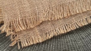 Kenarları yıpranmış çuval bezi, doğal dokuyu ve dokumayı gösteren yakın çekim. Döndürme