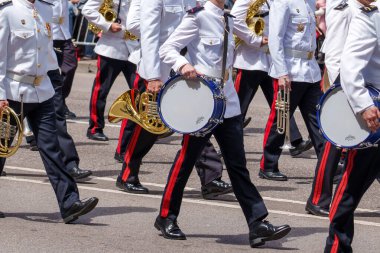 Oviedo, İspanya - 25 Mayıs 2024: Davulları ve pirinç müzik aletleri olan, siyah pantolonlu, beyaz üniformalı bir askeri bando sokakta yürüyor