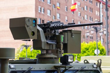 Oviedo, İspanya - 25 Mayıs 2024: askeri bir araca makineli tüfek monte edildi. Fıçı bulanık şehir manzarası arkaplanı ile görülebilir bir kapsam ile genişletildi