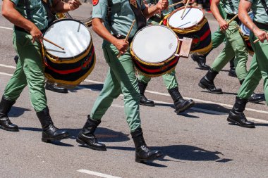 Oviedo, İspanya - 25 Mayıs 2024: Yeşil üniformalı bir grup askeri davulcu bir geçit töreninde enstrümanlarını hassasiyetle ve ritimle çalıyorlar.