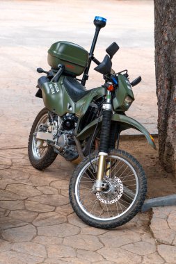 Oviedo, İspanya - 25 Mayıs 2024: Yeşil İspanyol Ordusu askeri motosikleti asfalt bir alanda bir ağacın yanına park edildi