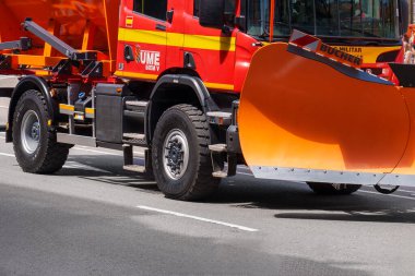 Oviedo, İspanya - 25 Mayıs 2024: Güneşli bir günde şehir yolunda turuncu bir sabanla kırmızı askeri acil durum kamyonu