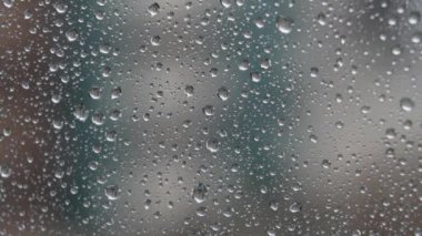 Şiddetli bir rüzgarla yağmur damlaları pencere camına düşer. Yağmurlu bir iklim. Islak sıçrama yüzeyi. Soyut görünüm