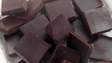 Taze doğranmış siyah çikolata parçaları beyaz, açık kağıtlı ambalajlar, pişirmeye ya da eritmeye hazır. Döndürme