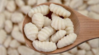 Tahta bir kaşığa yerleştirilmiş taze el yapımı patates gnocchi. İtalyan mutfağı ham malzemesi.