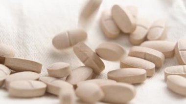 Tarafsız bir kumaş yüzeyine düşen bitkisel takviyeler. Genel sağlık geliştirme ve sağlık keşfi için doğal uropati hapları. Ağır çekim. Makro çekim